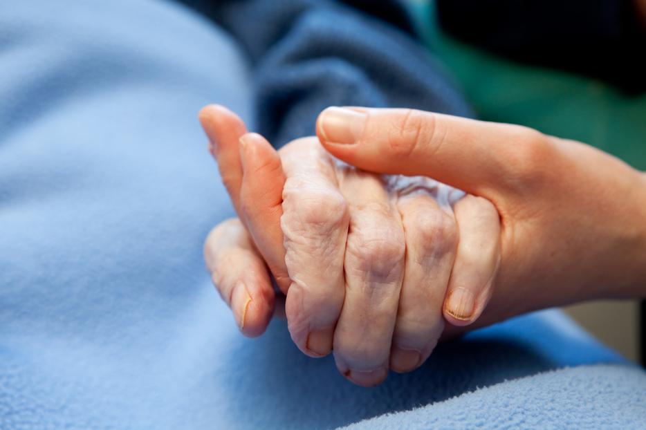 A woman holding the hand of an elderly person at a hospital.