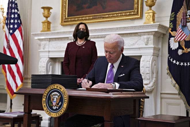 President Joe Biden signs an executive order after speaking about his administration's COVID-19 response on Friday.  His chief health official said the federal public health emergency declared because of the pandemic is expected to last through the end of the year.