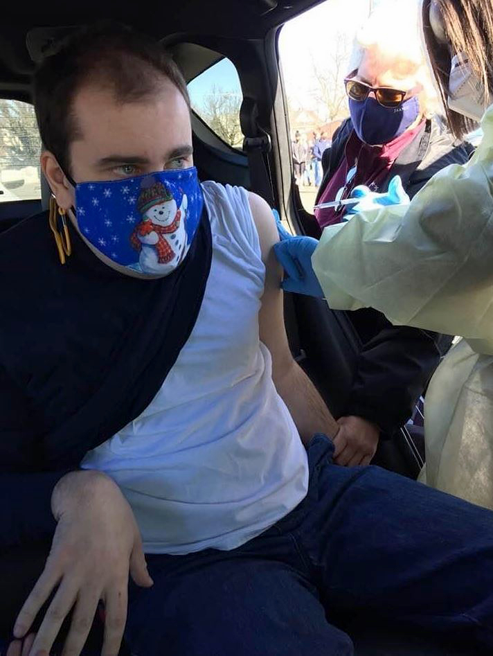 Evan Hookey, 29, of Princeton, New Jersey, received his first Covid-19 shot from a mobile unit working at Trenton Central High School.  The in-vehicle shot reduces waiting time and potential virus exposure for people like Evan with autism and others with physical and developmental disorders.