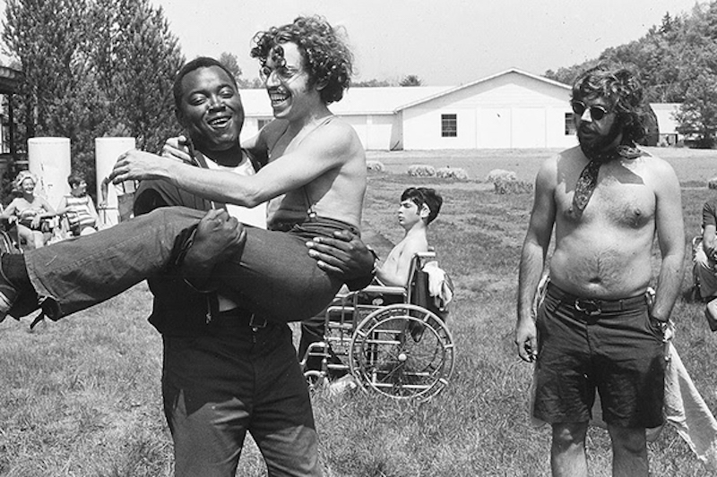 man holding another man at a summer camp