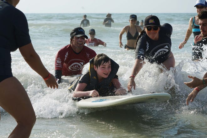 During an event in 2019, Life Rolls On and Ocean Cure supporters help a disabled youth enjoy the ocean on Carolina Beach. [WENDY JACKSON/LIFE ROLLS ON]