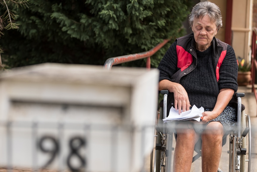 a woman in a wheelchair looks at documents