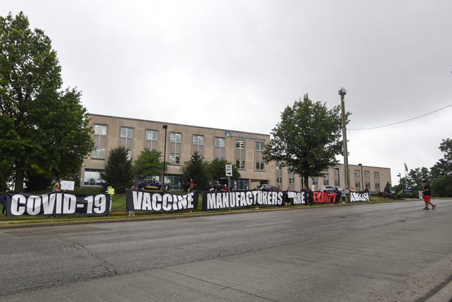 Protesters gather across from the Hamilton County Public Health Building in the Corryville neighborhood of Cincinnati and display anti-vaccine signs to passing cars on William Howard Taft Road on Monday, August 9, 2021.