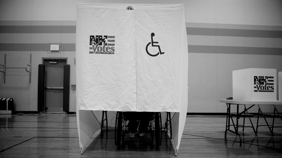 A person using a wheelchair votes in a wheelchair-accessible voting booth.