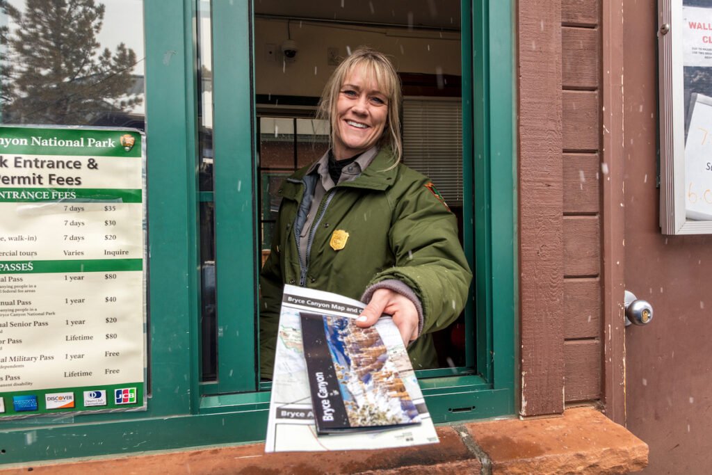 Female blonde National Park ranger hands out leaflet through window in Bryce National Park, Utah.