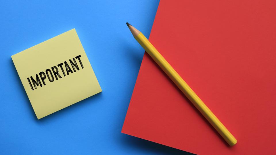 Yellow Post-It with IMPORTANT in bold letters, on blue and red papers with pencil