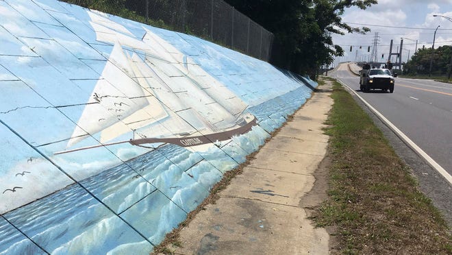 Traffic passes a mural of the slave ship Clotilda along Africatown Boulevard in Mobile, Ala.