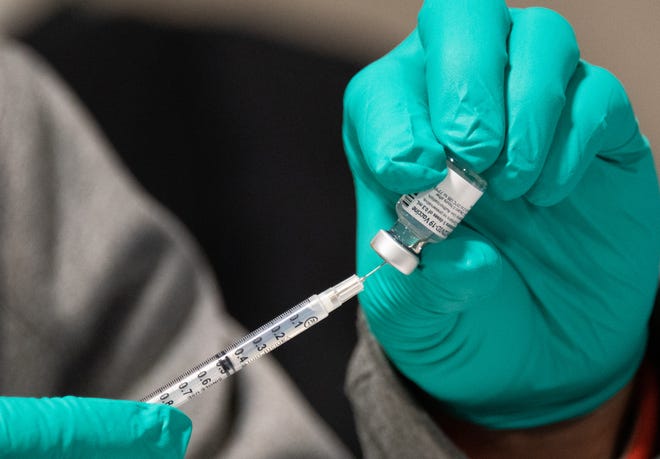 Medical workers draw COVID-19 vaccinations from vials into syringes at the Ingham County's drive-through vaccination center in the MSU Pavilion on Thursday, February 4, 2021.