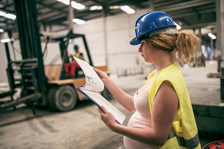 Pregnant woman with hard hat on a construction site